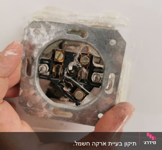 יד מחזיקה שקע חשמלי עם חוטים חשופים